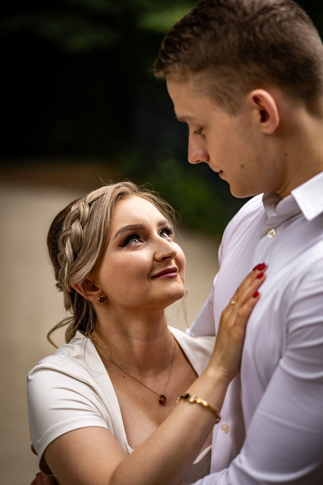 A tender moment between a couple in white clothing as they gaze at each other.