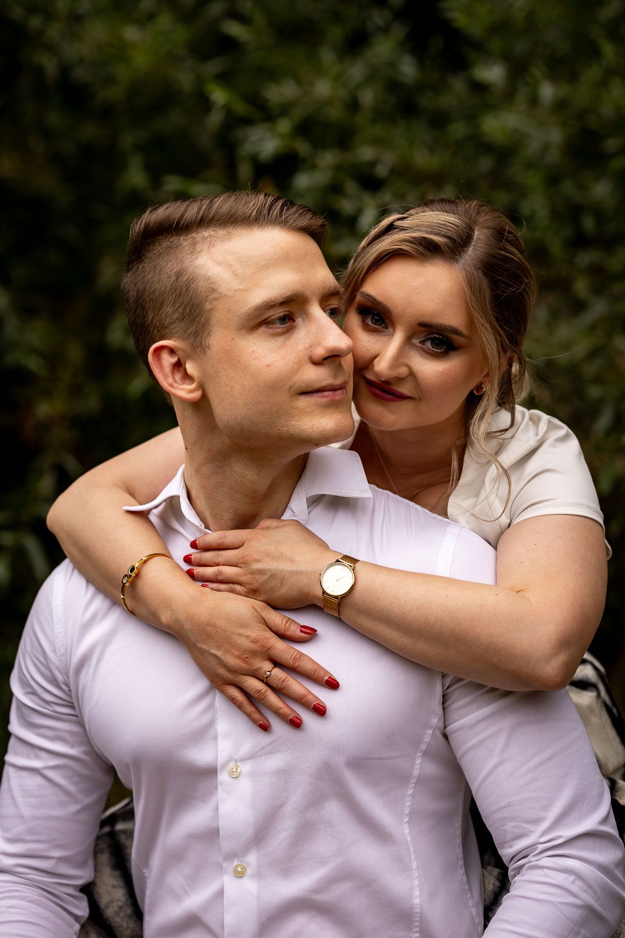 A romantic couple in white shirts share an intimate moment against a natural backdrop.