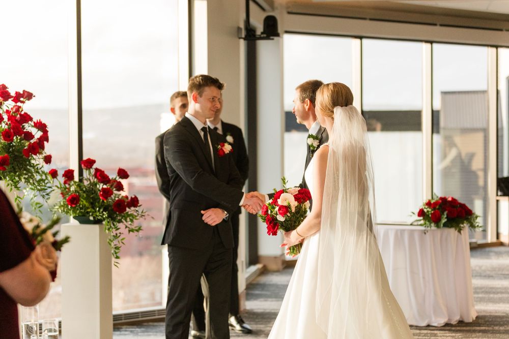 A wedding ceremony montage showing multiple angles of an elegant indoor venue with red floral arrangements and white decor.
