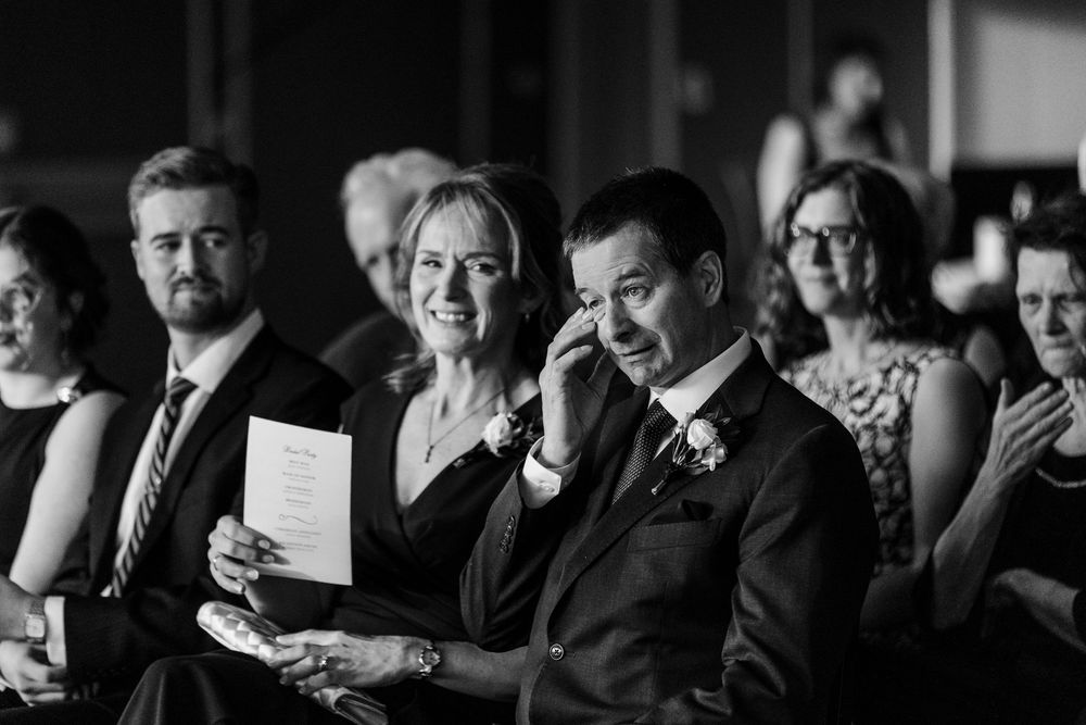 Black and white photo showing emotional reactions of wedding guests during a ceremony.
