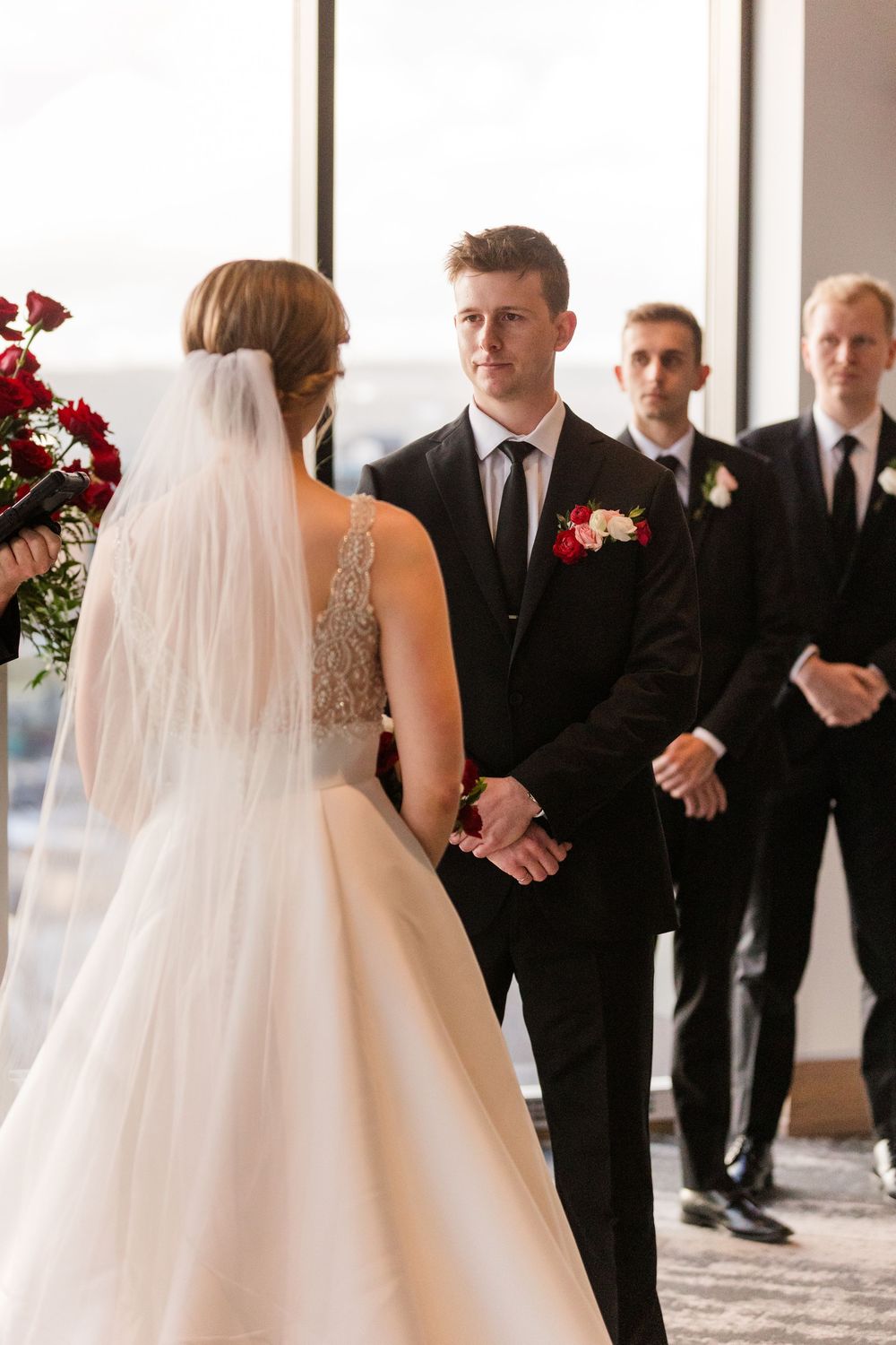 Wedding ceremony processional with bride in white gown and veil walking past guests in formal attire.