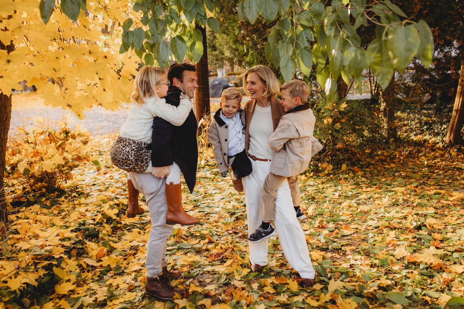A group dances and plays in fallen autumn leaves on a sunny day while wearing white outfits.