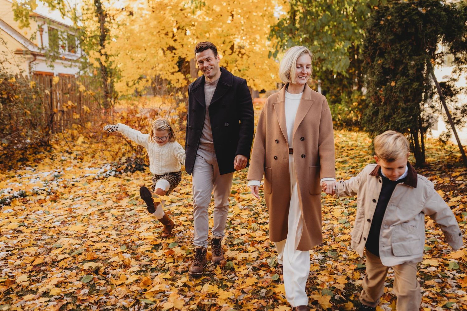 Couple walking together through vibrant yellow autumn leaves in a park during golden hour.
