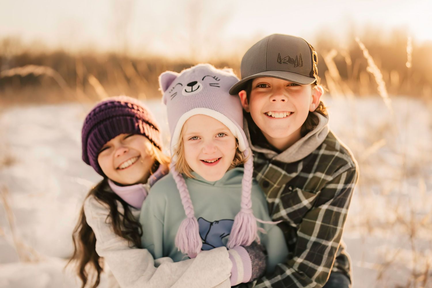 siblings hug as they play in the snow during their mini session at French park