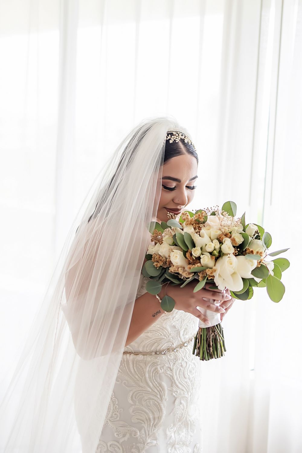 Bride holding her bouquet near the window, glowing in soft natural light at Moon Palace.