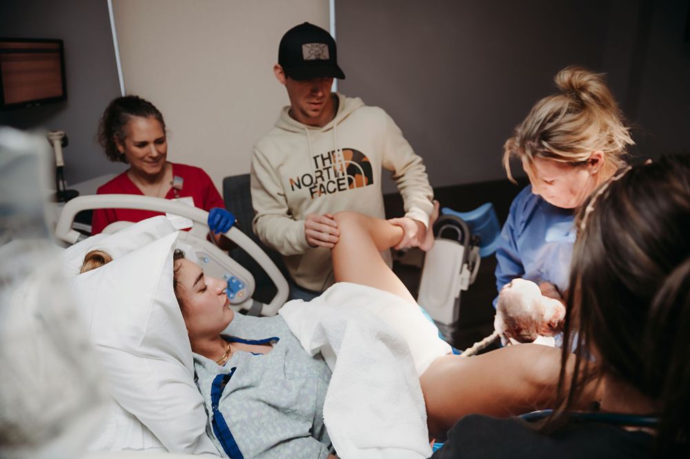 Father watches as a mother pushes out their brand new baby.