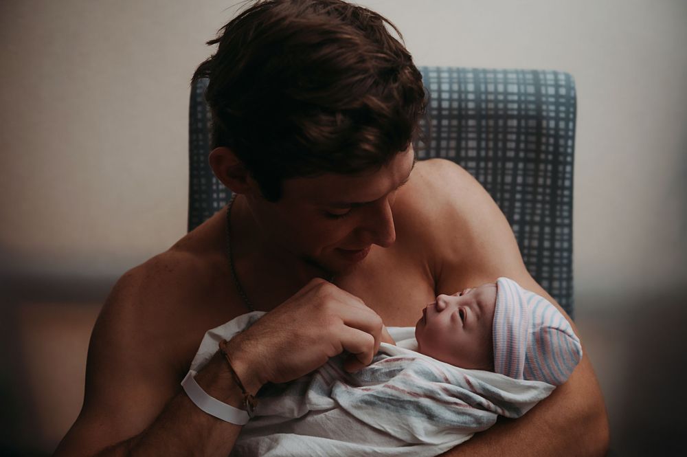 Brand new father holds his newborn after her birth.