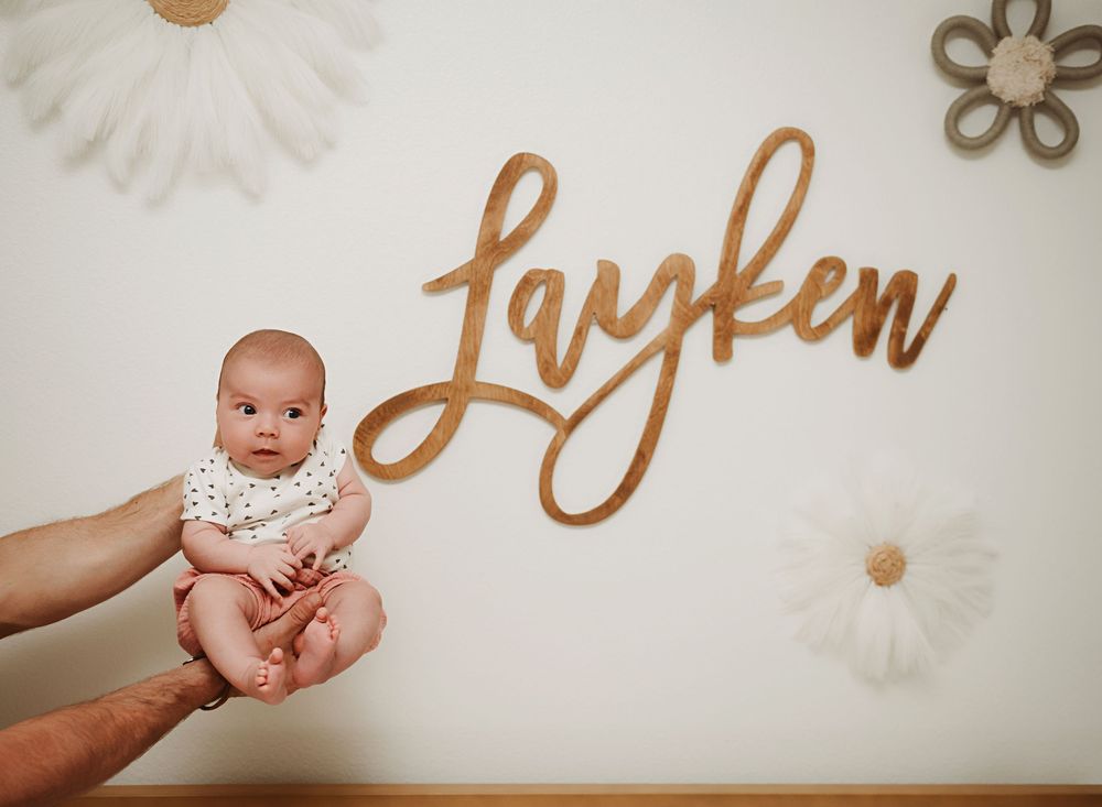 A collection of baby photos arranged in a horizontal strip showing different poses and moments with gold lettering.