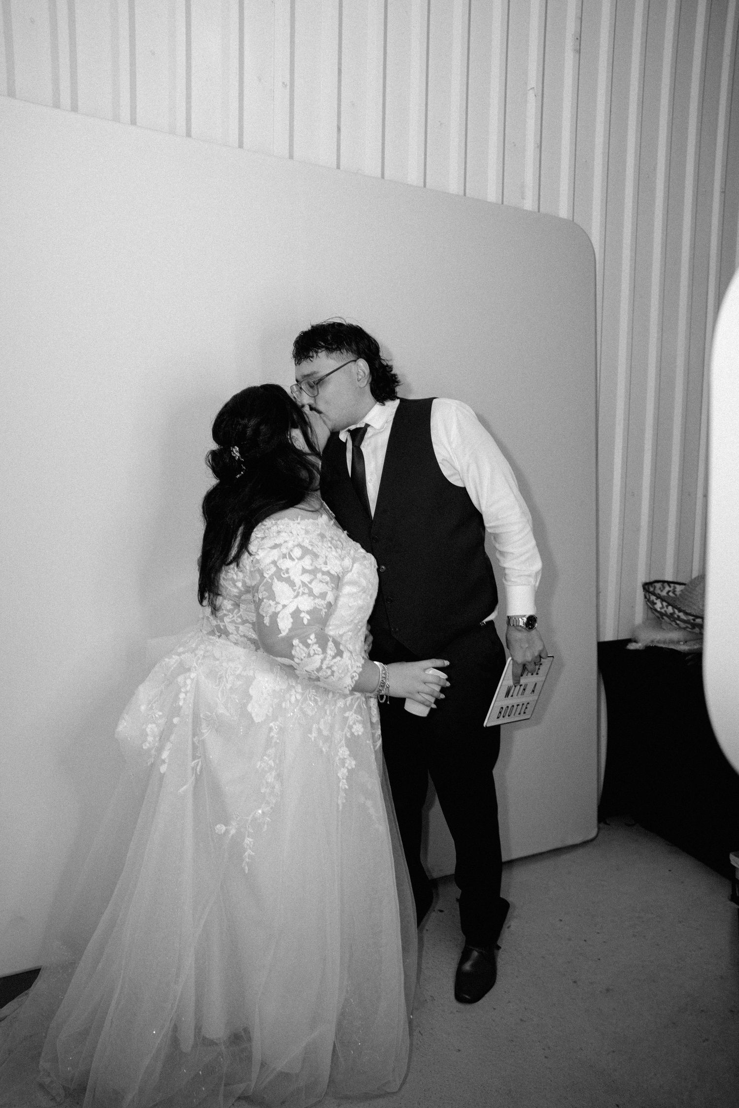Black and white photo of bride and groom sharing a kiss at their wedding reception.