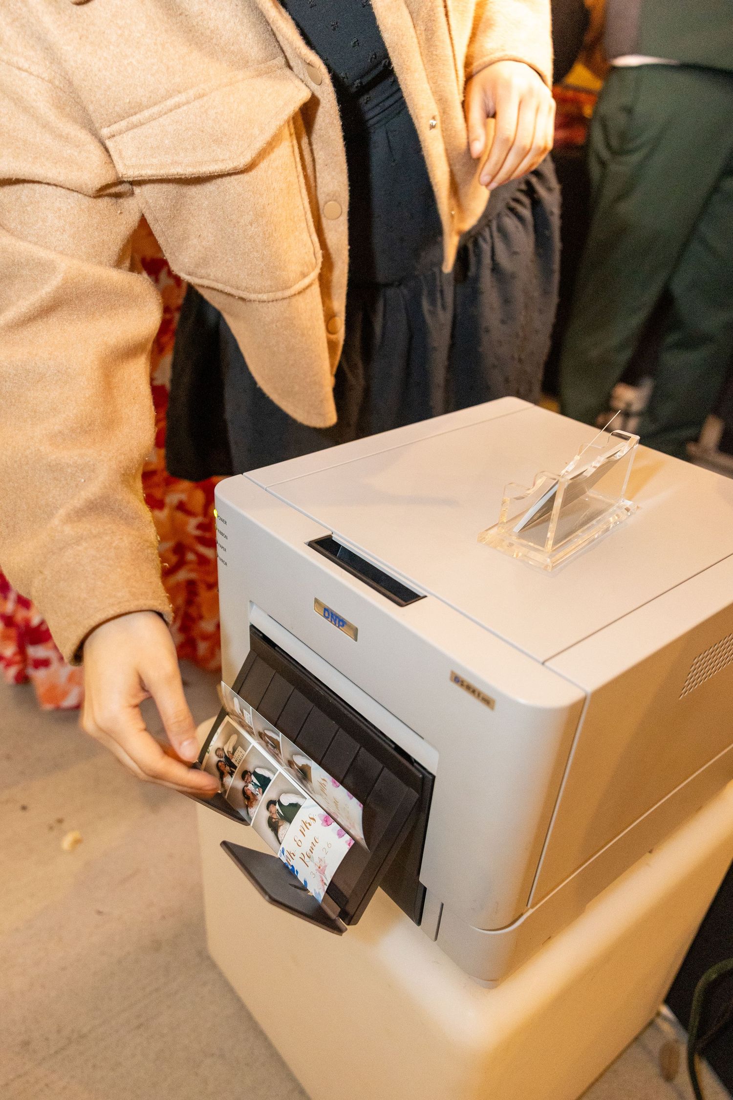 Guest retrieving printed photo strip from a photo booth printer at a wedding.