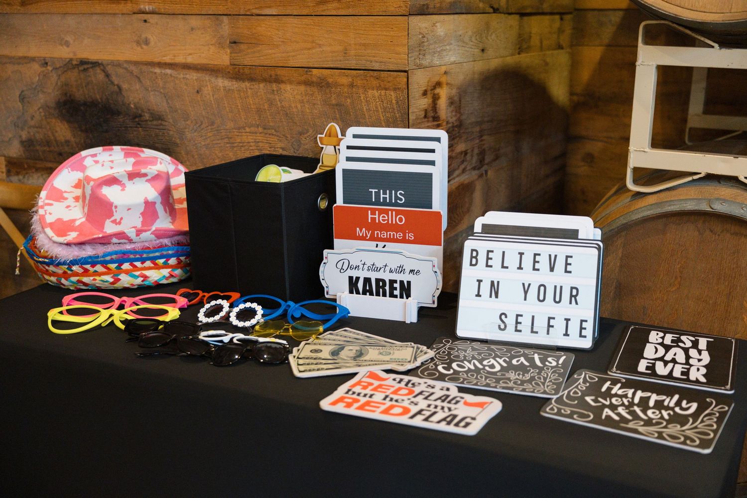 Photo booth prop table displays fun accessories including hats, glasses, and colorful signs at a wedding reception.