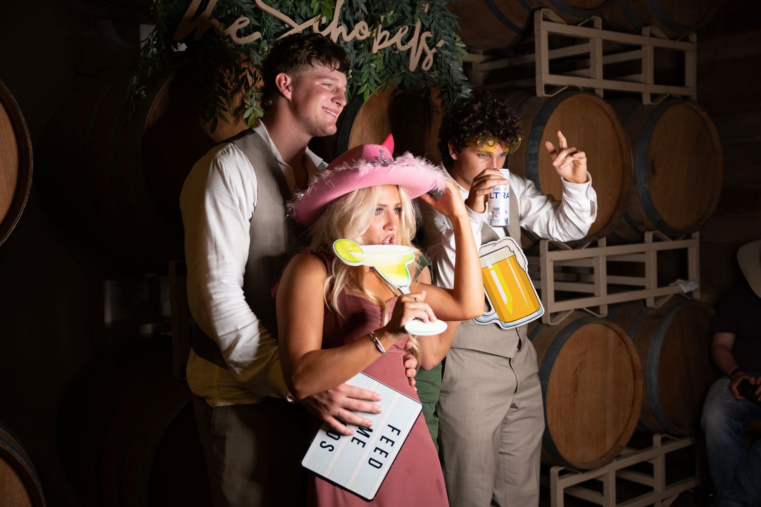 Group of friends posing with fun props at the photo booth during a wedding celebration.