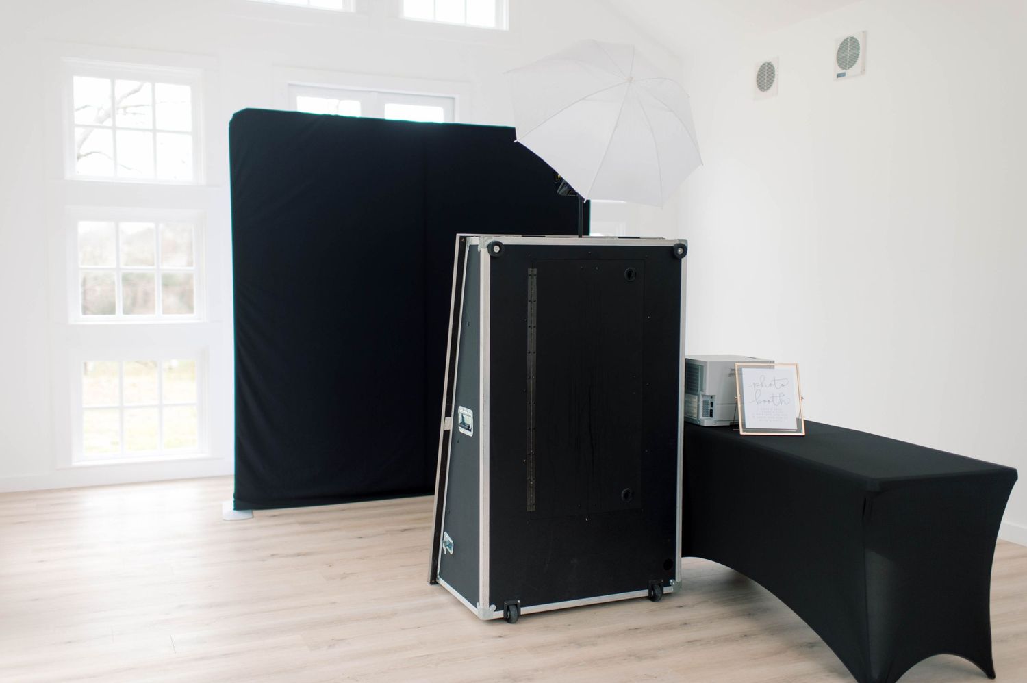 Professional photo booth setup with black backdrop, lighting, and prop table.