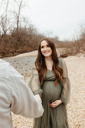 A couple shares candid moments outdoors on a rocky path during a winter photo session.