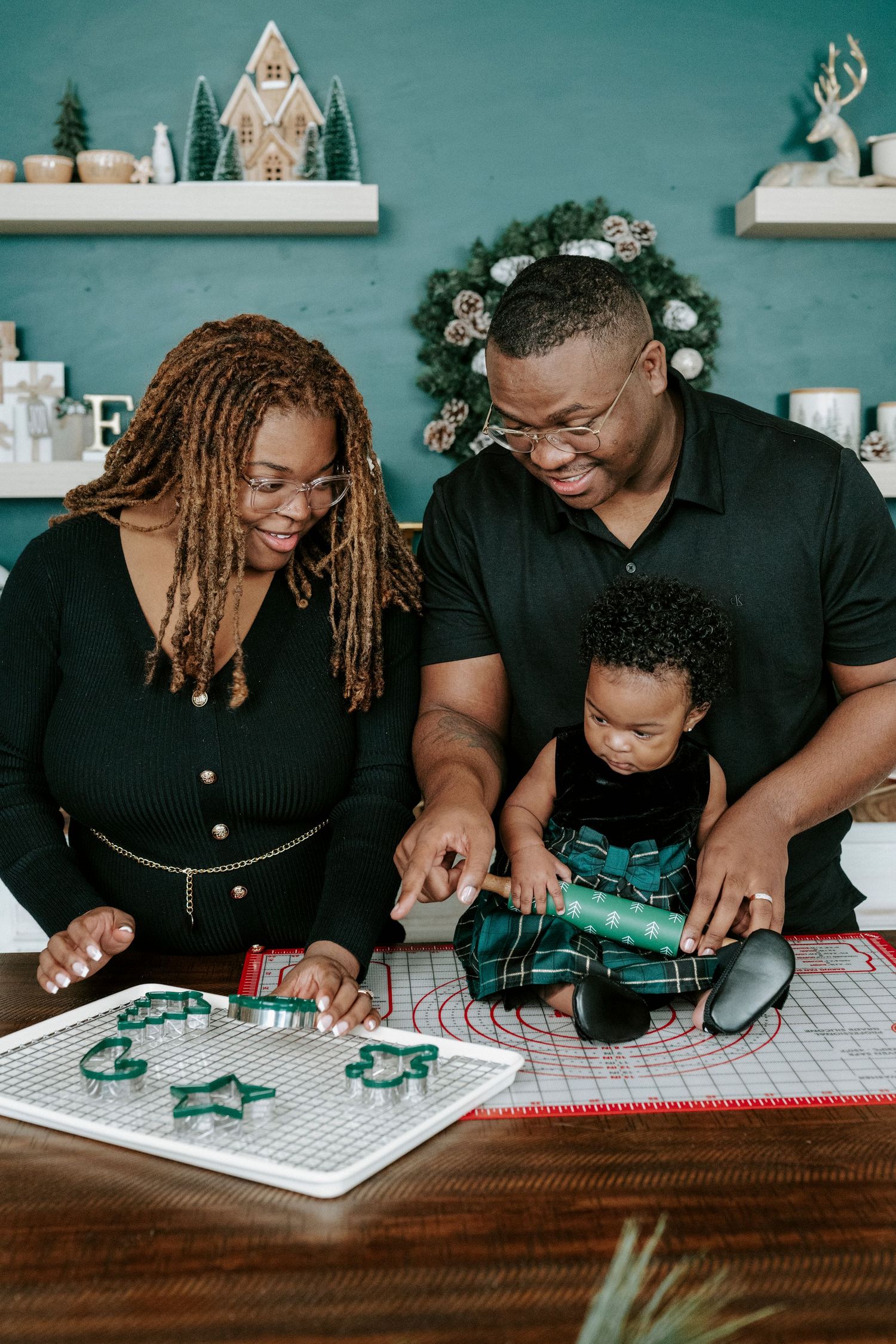 Family works together on an educational activity using a green electronic circuit board on a patterned tablecloth.