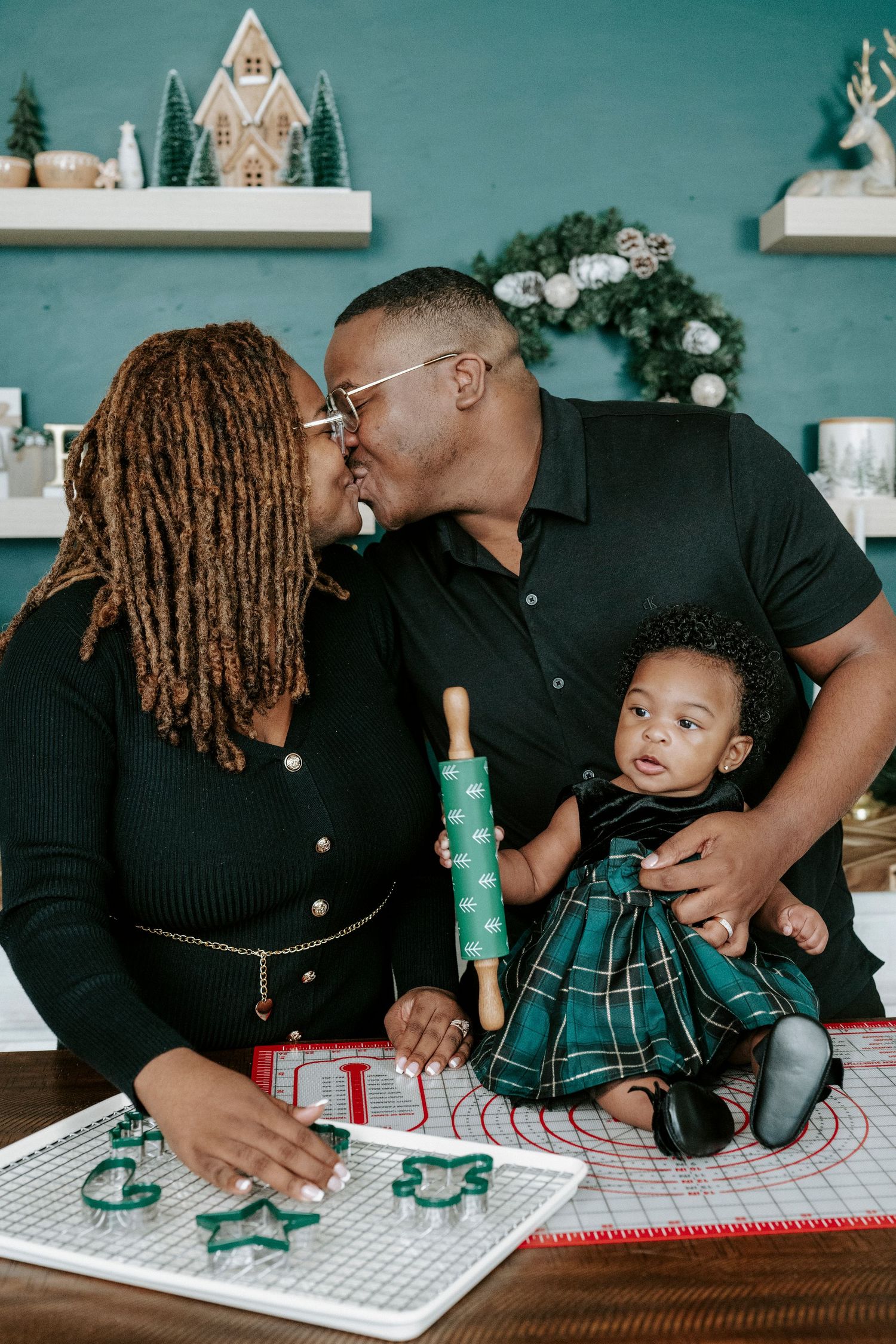 A family shares a tender moment while sitting at a table with green cans and white decor in the background.