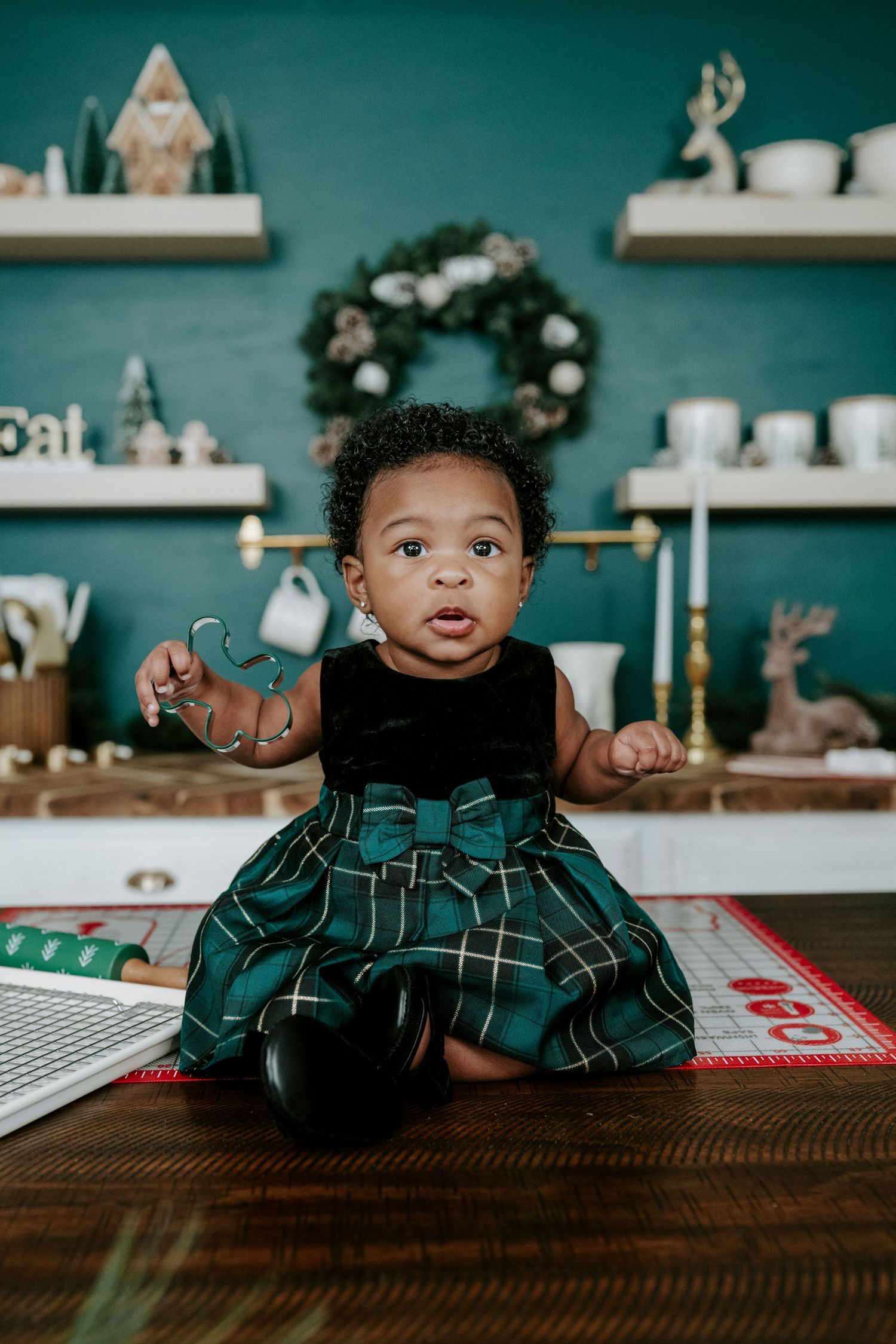A series of photos showing a small child in a plaid green outfit peeking over a wooden table in a cozy kitchen setting.