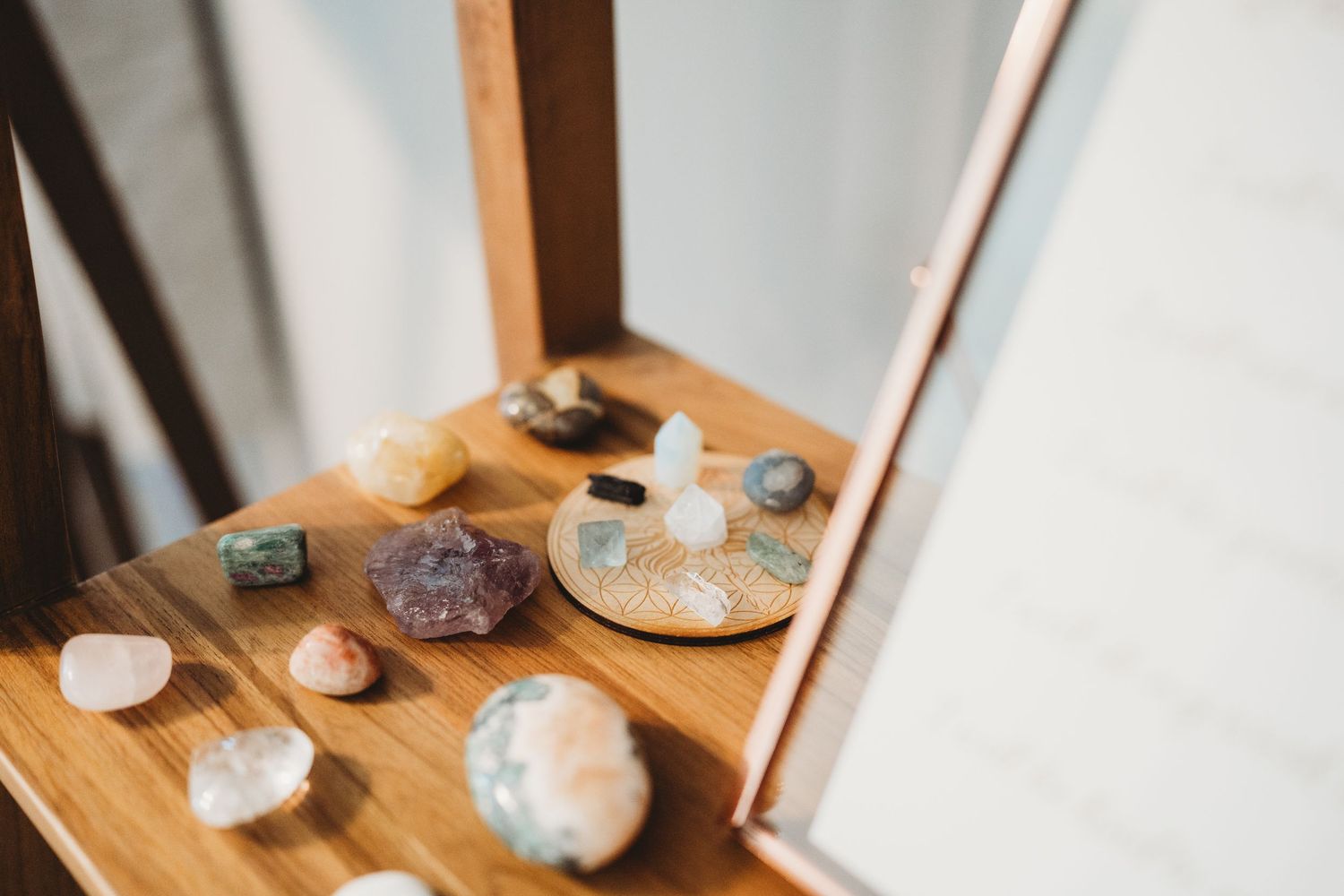 A collection of crystals and healing stones displayed on a wooden surface near a corner wall.