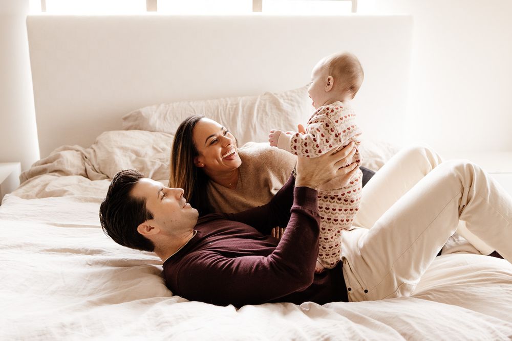 Parents laugh with their baby at their in-home session