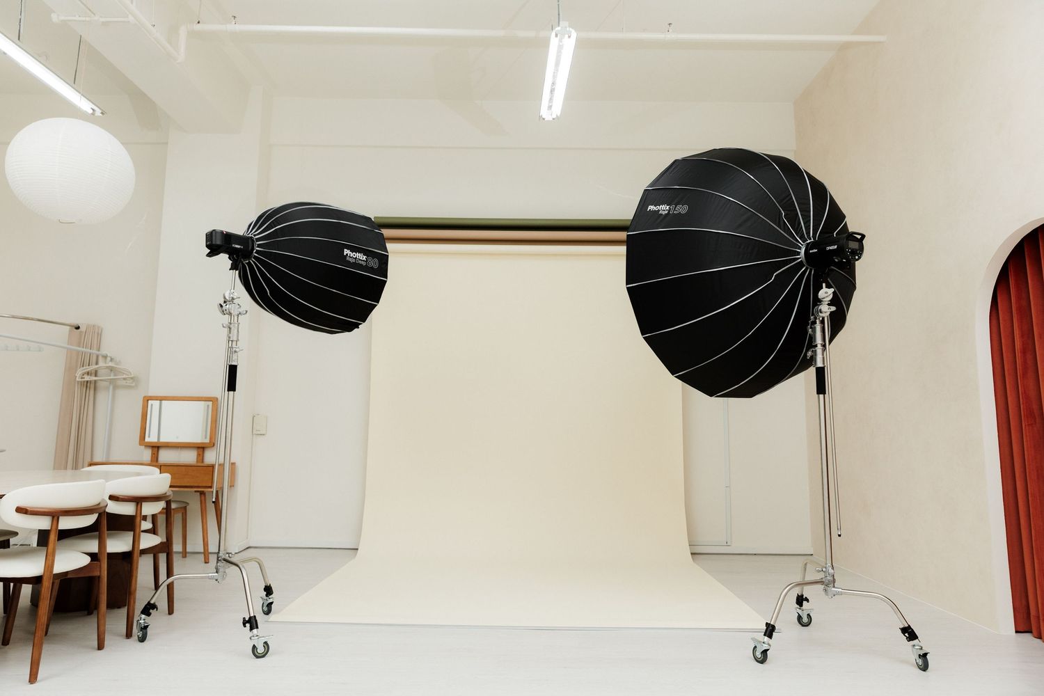 Photography studio setup with black softboxes, lighting equipment, and white walls in a professional workspace.