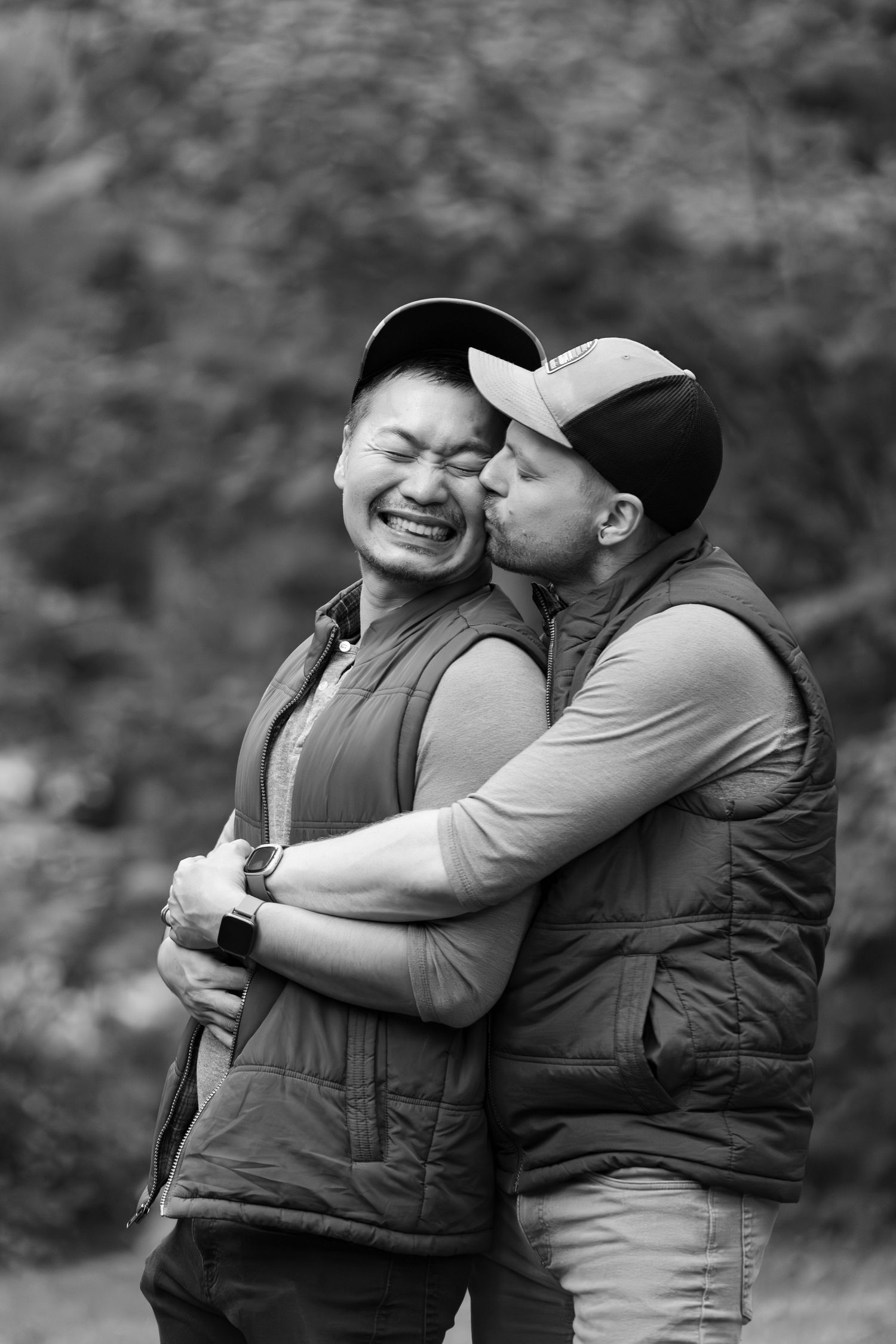 A couple in puffy vests share an intimate embrace and laugh together in a black and white photo series.