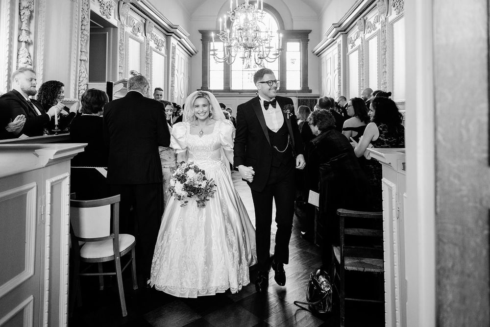 Black and white wedding photos arranged in a horizontal collage showing formal celebration moments in an elegant venue.