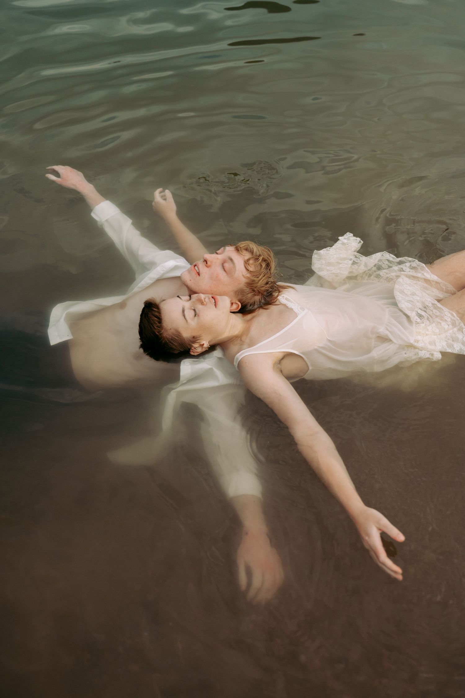 A figure in a white dress floats ethereally in dark water creating a dreamy underwater scene.
