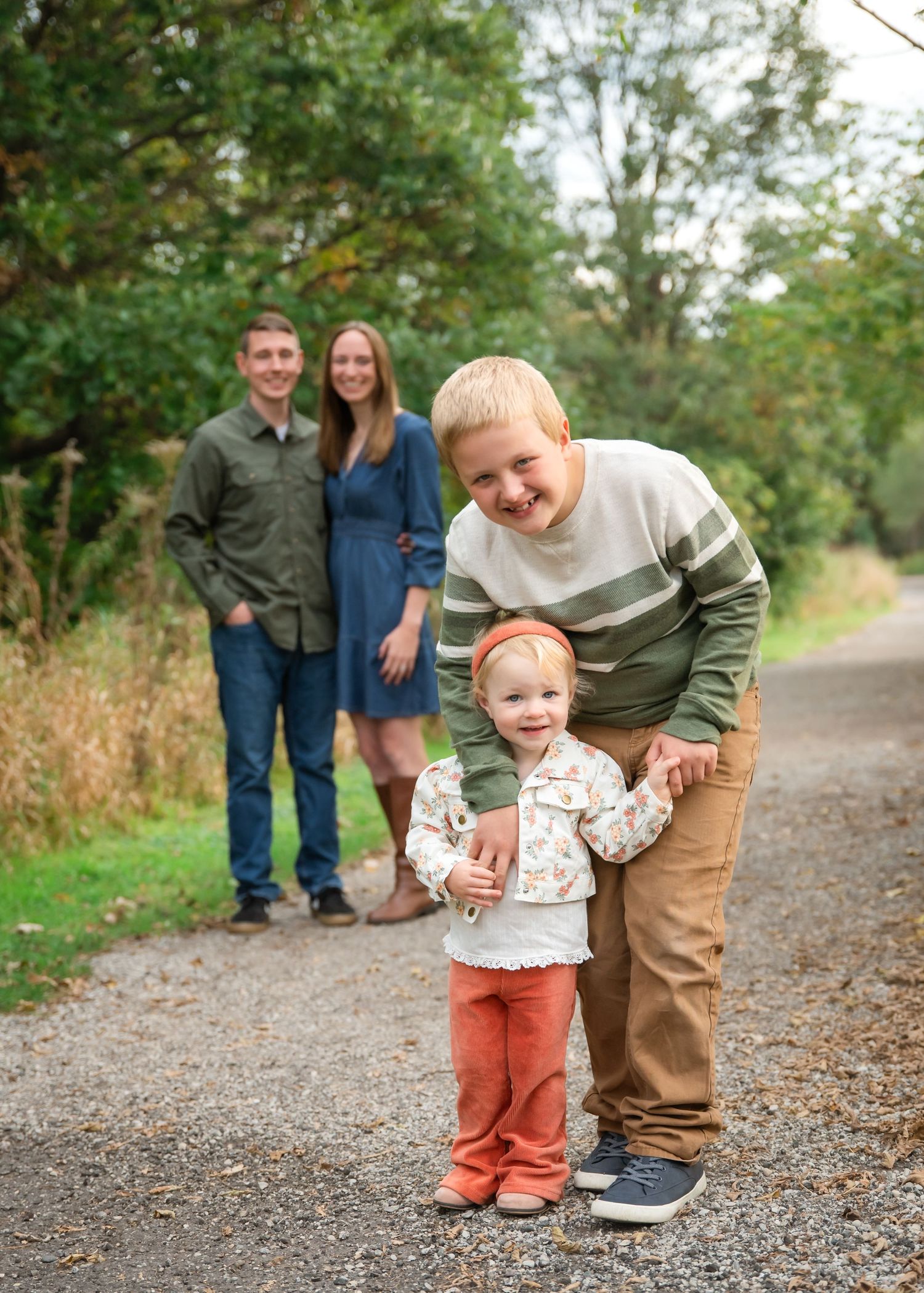 Family walking together on a gravel path through autumn foliage, captured in a series of candid moments.