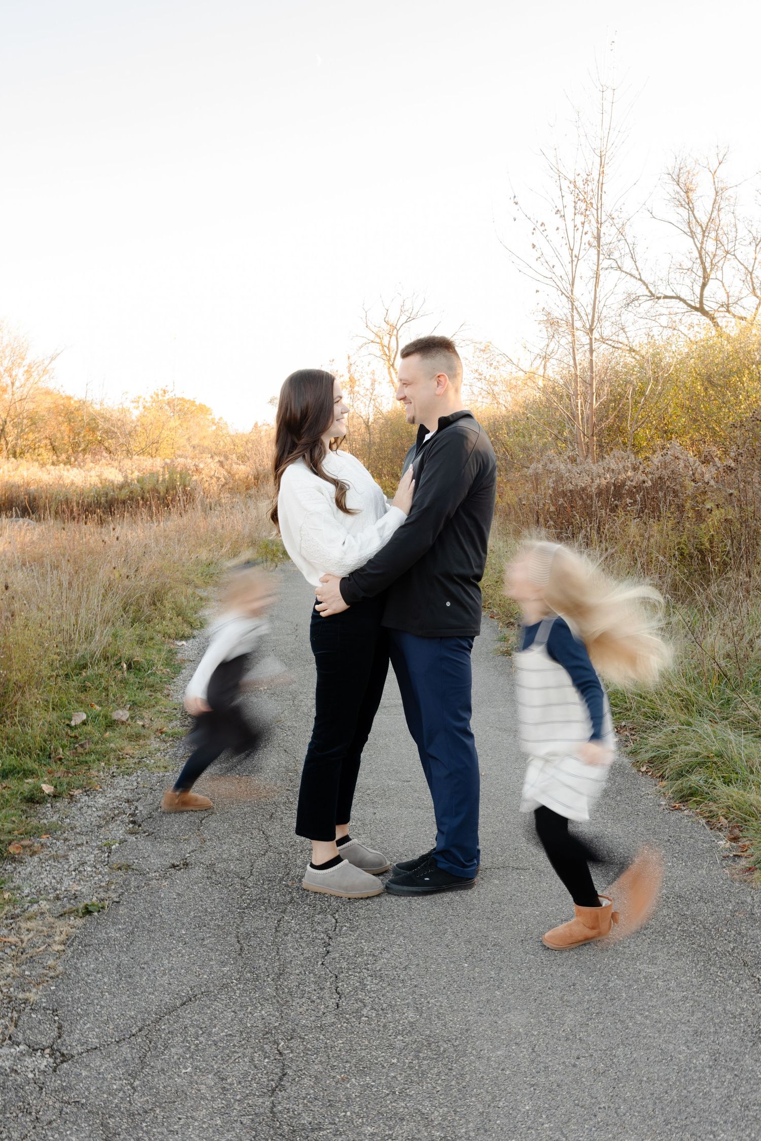 Family enjoying playful moments together during autumn photoshoot with golden foliage in background.