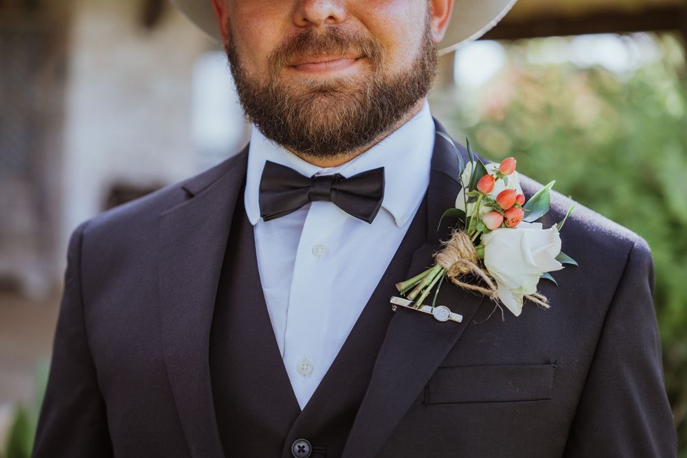 Close-up of formal attire with black bow tie and floral boutonniere.