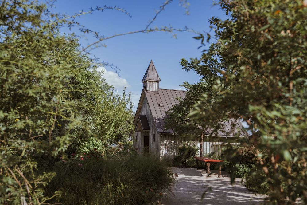 Chapel steeple visible through tree branches against blue sky.