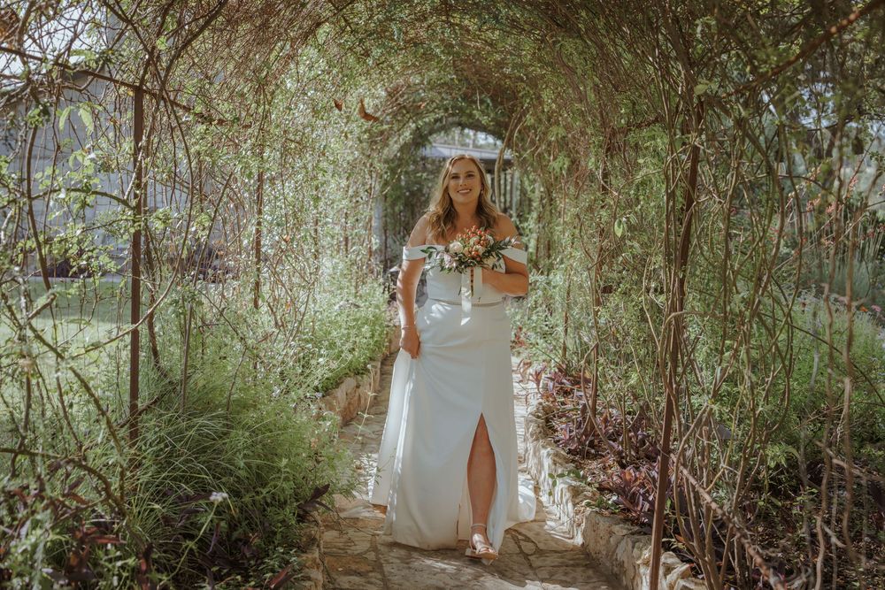 White wedding dress photographed in lush garden setting with natural lighting.