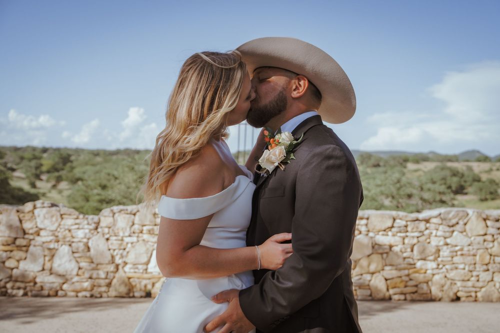 A rustic stone wall backdrop frames an intimate outdoor wedding ceremony.