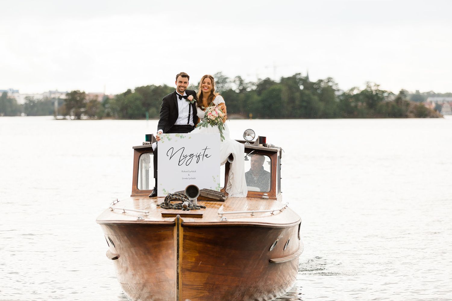 A small wooden boat travels across a calm lake with trees lining the distant shore.