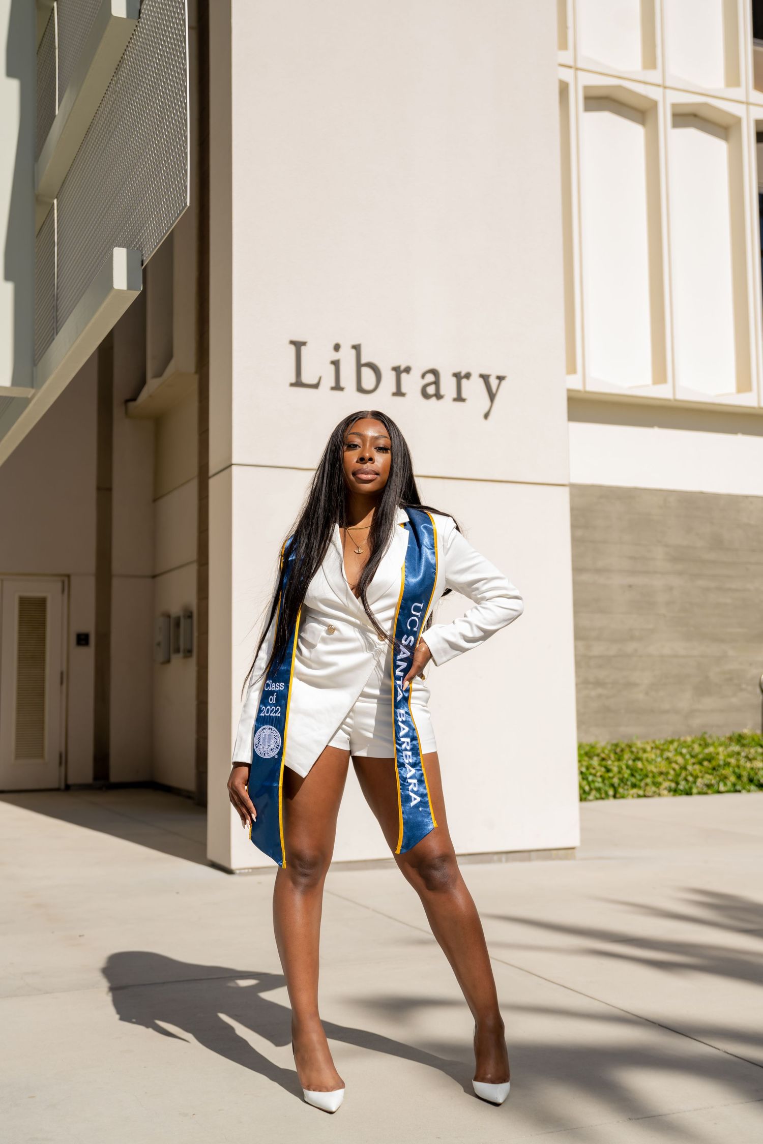 A person in a white blazer and blue shorts poses in different dynamic stances against a light-colored building exterior.