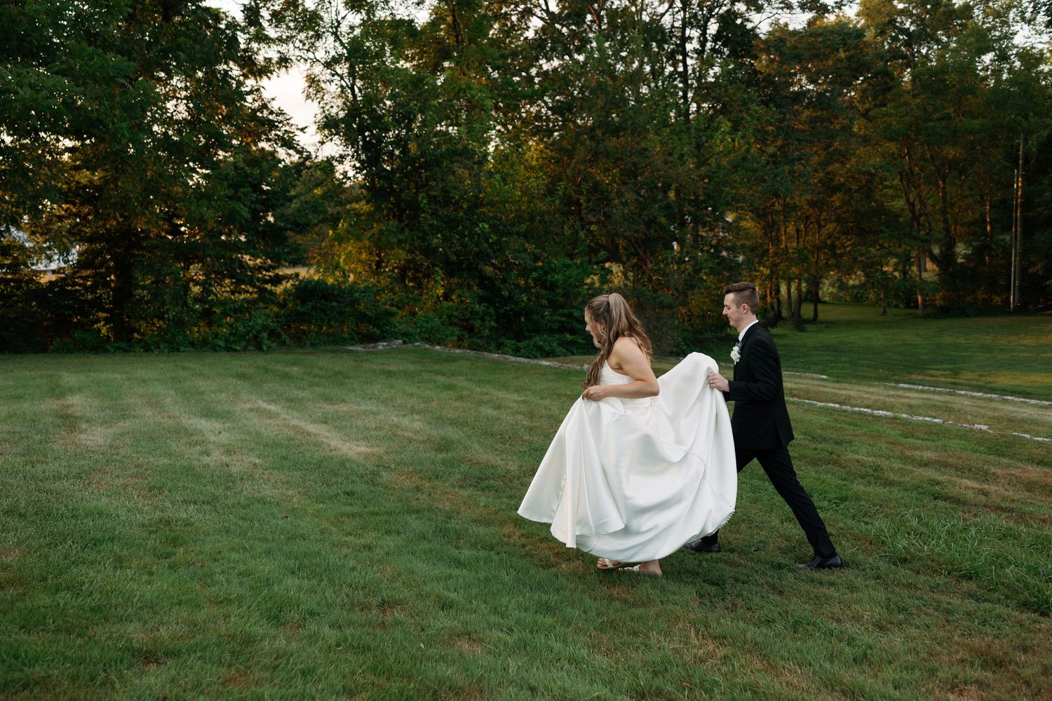 Black and white wedding photo with a couple standing beside an ornate garden fountain with a chapel in the background.