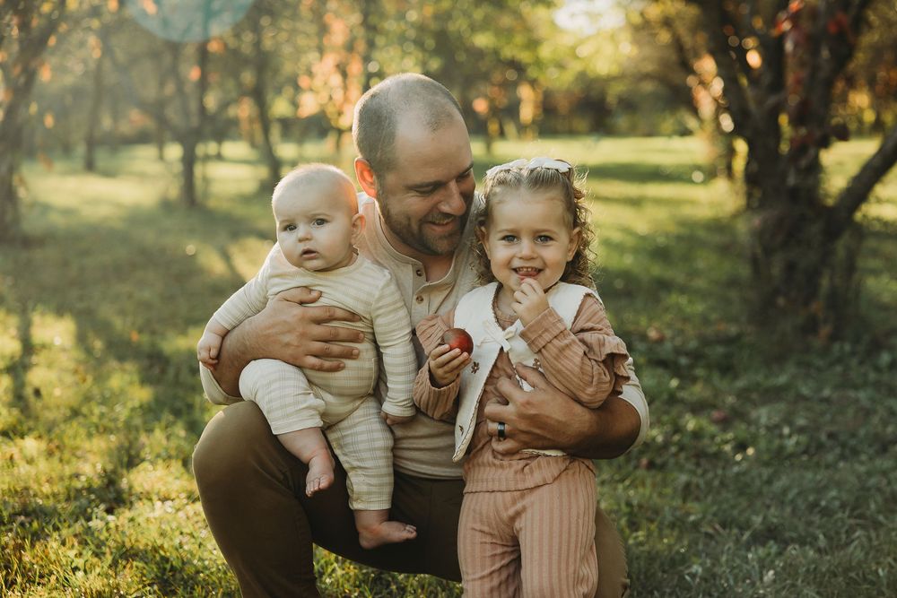 A heartwarming family moment captured in golden sunlight as they share joyful expressions in a park setting.