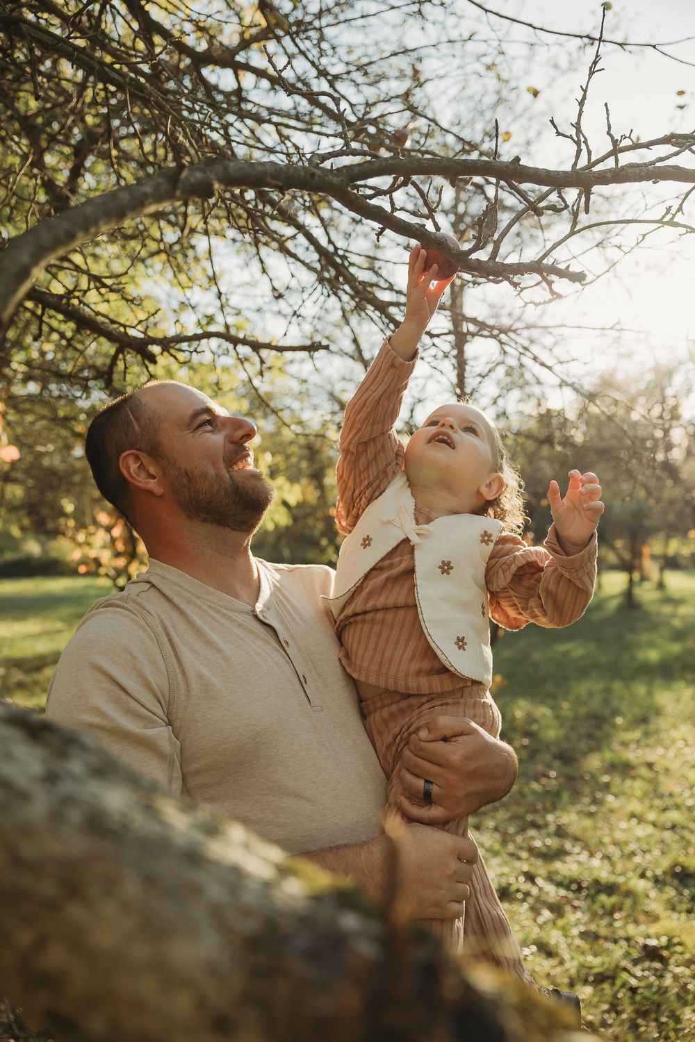 A parent and child share joyful moments together outdoors during golden hour in a natural setting.