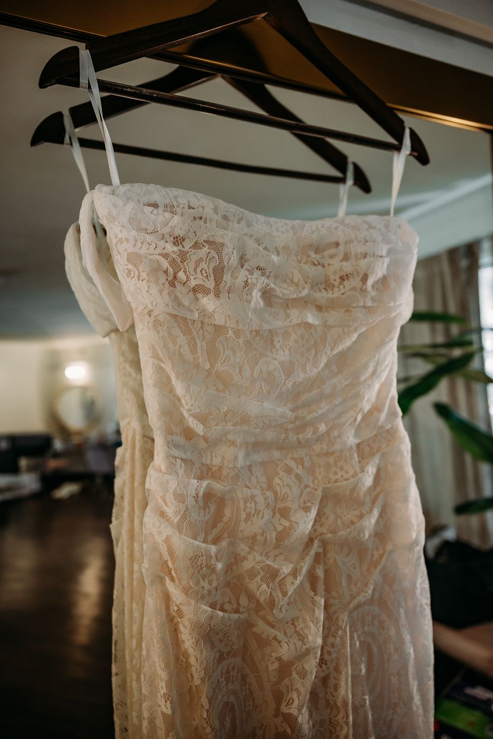 Detailed lace wedding dress hanging on display in natural light.
