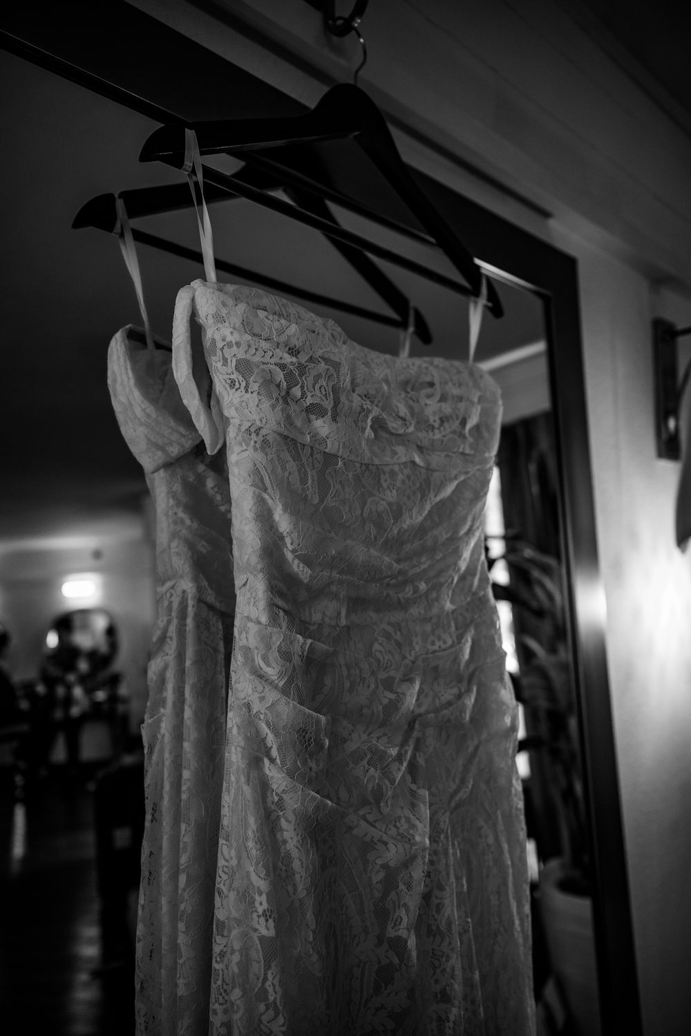 Dramatic black and white photo of a lace wedding dress on display.