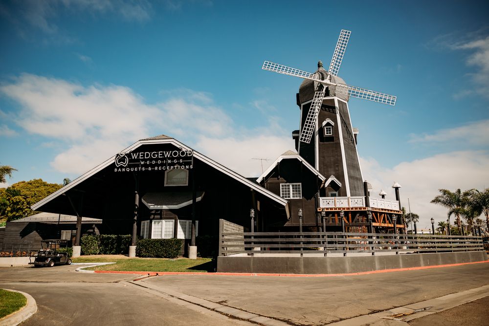 Panoramic view of rustic windmills and barn buildings under bright blue sky.