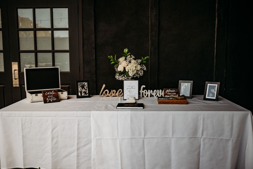 Long table with white tablecloth and framed photos arranged for wedding reception.