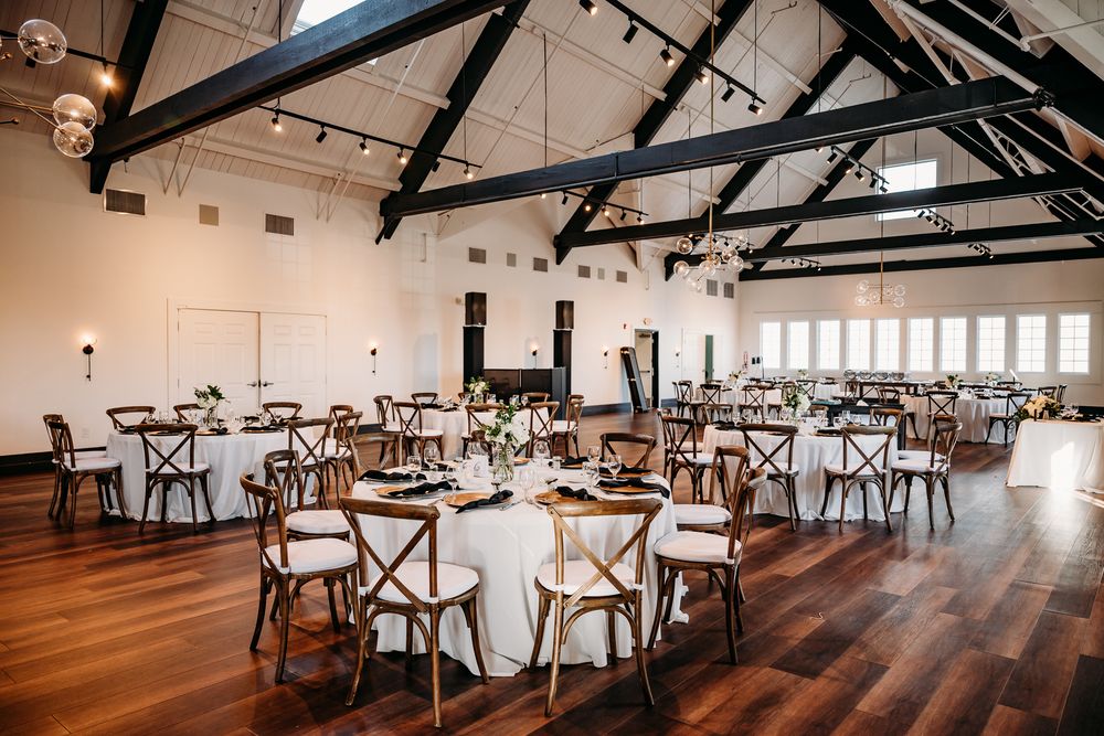 Elegant reception hall with exposed wooden beams and round tables set for dining.