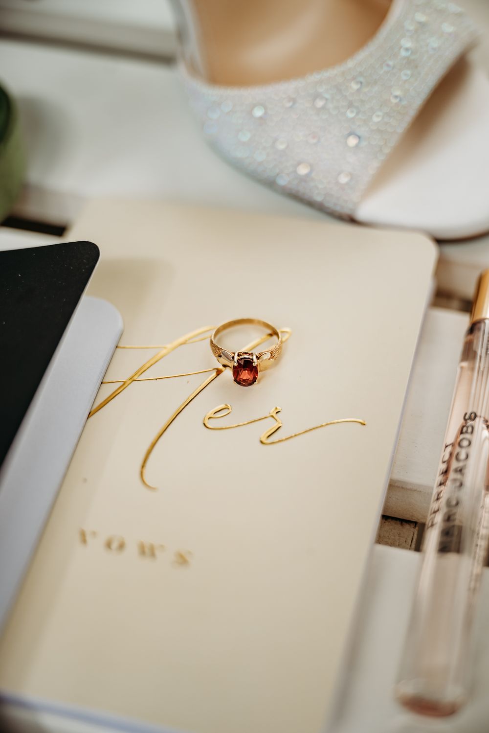 Wedding rings and vows displayed on an elegant cream-colored paper with gold lettering.