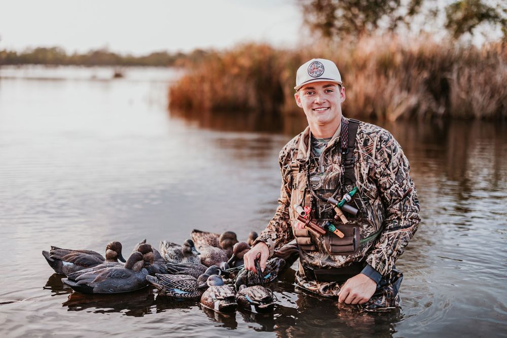 Hunter with decoys and gear prepares for waterfowl hunting in a wetland setting.