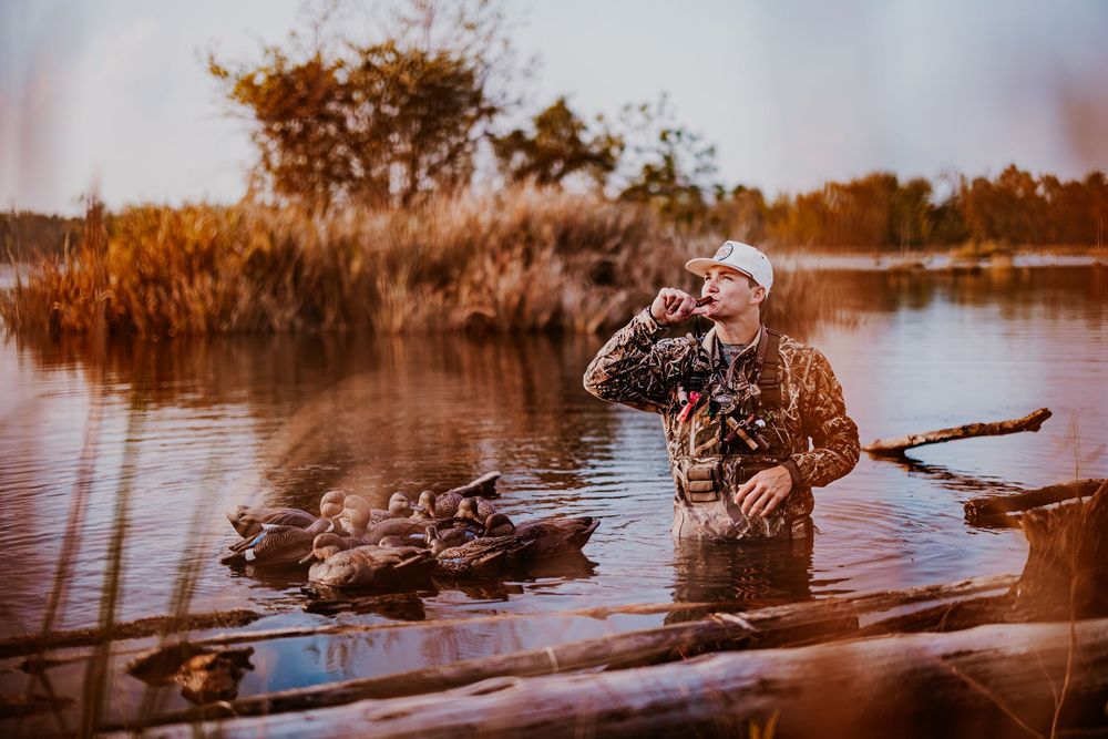 Panoramic view of a hunter setting up decoys in golden autumn marsh light.