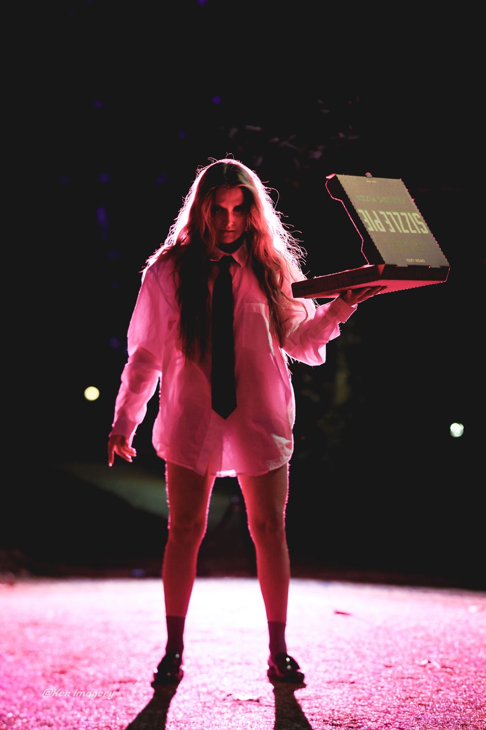A performer in a pink suit stands dramatically lit on stage in a sequence of dynamic poses under red lighting.