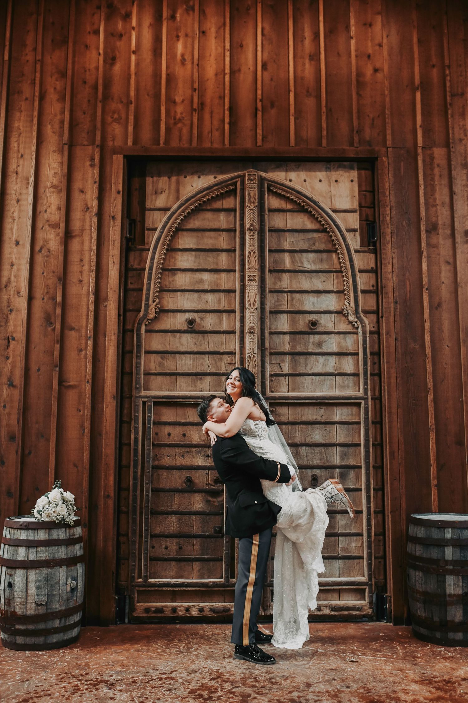 Editorial wedding shot of couple in front of warm-toned wooden doors at Lucky Spur Ranch.
