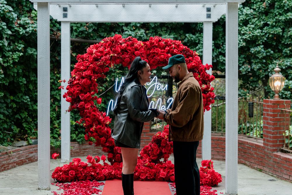 White garden pergola adorned with bright red rose arrangements creates an elegant walkway.