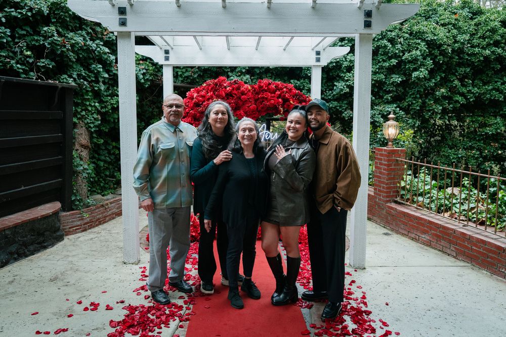 Red carpet and floral arch create a romantic outdoor setting under a white pergola.
